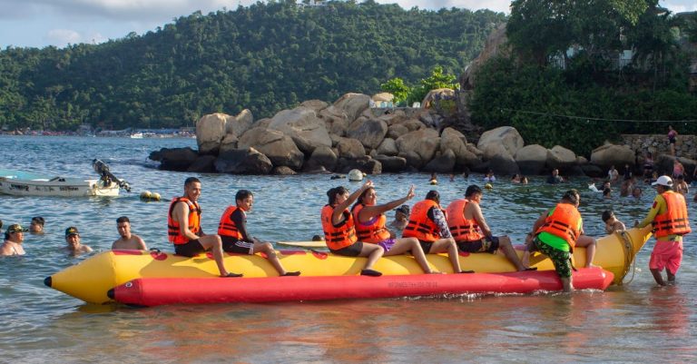 Erstes Meerziel Spanien oder Griechenland Group enjoying a thrilling banana boat ride at Acapulco beach under the sun.